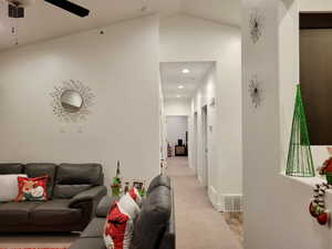 Carpeted living room featuring ceiling fan and lofted ceiling