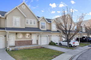 Townhome / multi-family property featuring a garage and a front yard