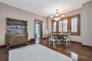 Dining space with an inviting chandelier and dark wood-type flooring