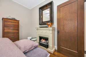 Bedroom with crown molding and dark wood-type flooring