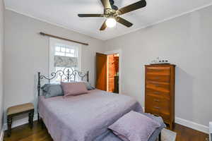 Bedroom featuring dark wood-type flooring, ceiling fan, and crown molding