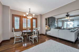 Dining area featuring ceiling fan with notable chandelier, ornamental molding, a wealth of natural light, and dark hardwood / wood-style floors