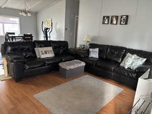 Living room with an inviting chandelier, lofted ceiling, and hardwood / wood-style flooring