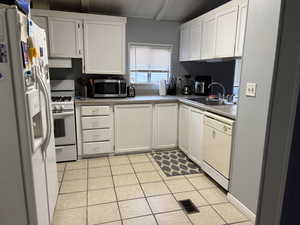 Kitchen featuring white cabinetry, sink, white appliances, and ventilation hood