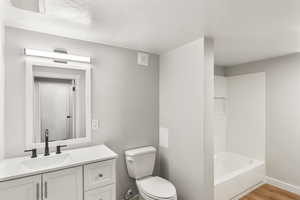 Bathroom with wood-type flooring, vanity, a textured ceiling, and toilet