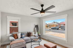 Living room with ceiling fan, wood-type flooring, and a textured ceiling