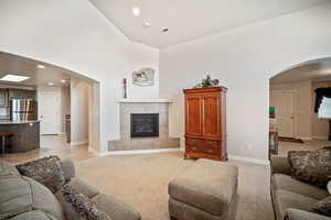 Living room with light carpet, a tile fireplace, and a high ceiling