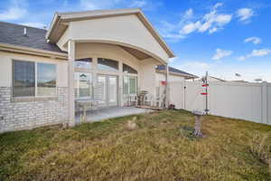 Rear view of property with a yard and a patio