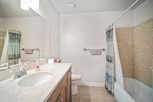 Full bathroom featuring tile patterned flooring, vanity, toilet, and shower / bath combo with shower curtain