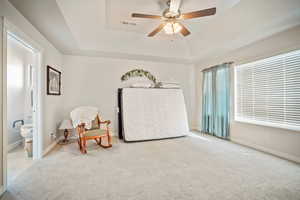 Sitting room featuring ceiling fan, light carpet, and a tray ceiling