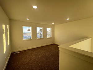 Empty room featuring dark colored carpet