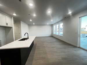 Kitchen featuring sink, white cabinets, hardwood / wood-style floors, and a kitchen island with sink