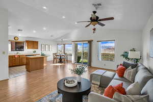 Living room with ceiling fan, vaulted ceiling, sink, and light hardwood / wood-style flooring