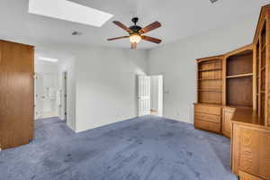 Interior space featuring carpet, ceiling fan, and a skylight