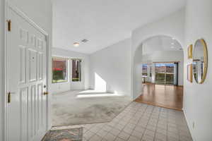 Foyer entrance with lofted ceiling, a healthy amount of sunlight, and light tile patterned floors