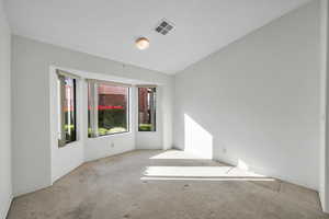 Carpeted spare room with lofted ceiling