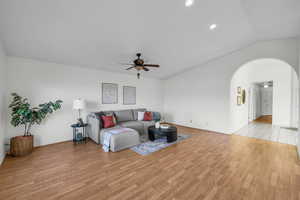 Living room with ceiling fan, vaulted ceiling, and light hardwood / wood-style flooring