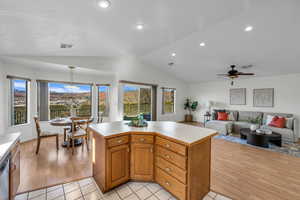 Kitchen with pendant lighting, light tile patterned flooring, a kitchen island, and lofted ceiling