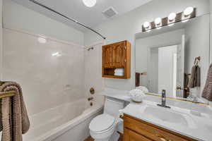 Full bathroom featuring a textured ceiling, vanity, toilet, and shower / washtub combination