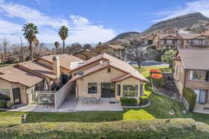 Rear view of house with a mountain view and a yard