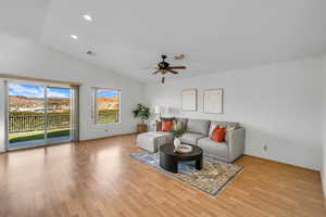 Living room with ceiling fan, light hardwood / wood-style floors, and lofted ceiling