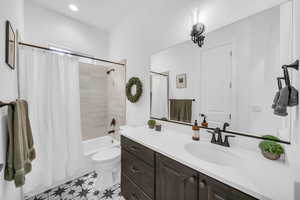 Full bathroom featuring toilet, shower / tub combo with curtain, and vanity