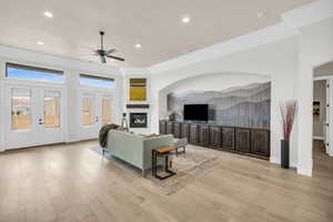 Living room featuring light hardwood / wood-style floors, ceiling fan, french doors, and ornamental molding