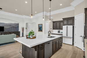 Kitchen featuring white fridge, dishwasher, hanging light fixtures, an island with sink, and sink