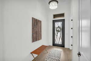 Foyer entrance with a high ceiling, an inviting chandelier, and light hardwood / wood-style flooring