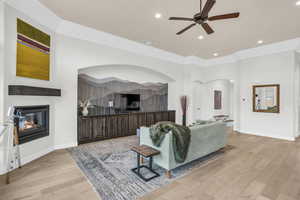 Living room with ceiling fan, crown molding, and light hardwood / wood-style flooring