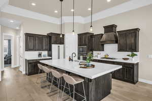 Kitchen featuring high quality fridge, custom exhaust hood, built in microwave, and hanging light fixtures