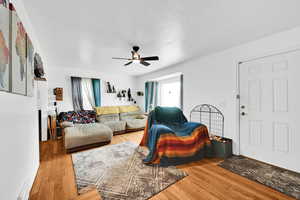 Living room with hardwood / wood-style flooring, ceiling fan, and a textured ceiling