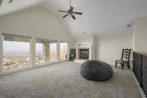 Living area with carpet flooring, ceiling fan, and high vaulted ceiling