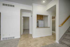 Kitchen with ornamental molding, light colored carpet, and white refrigerator