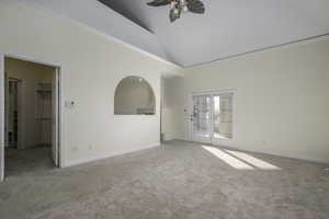 Empty room featuring high vaulted ceiling, french doors, crown molding, ceiling fan, and light colored carpet