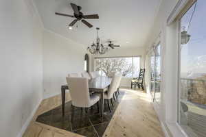 Dining area with ceiling fan with notable chandelier, wood-type flooring, and crown molding