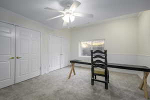 Office space with light colored carpet, ceiling fan, and crown molding