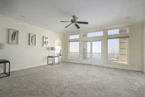 Unfurnished living room with ceiling fan, ornamental molding, and light carpet