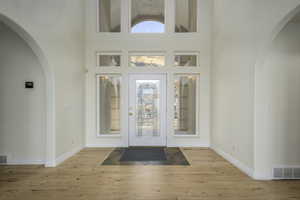 Entryway featuring light wood-type flooring and a towering ceiling