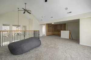 Living area featuring carpet flooring, ceiling fan, and high vaulted ceiling