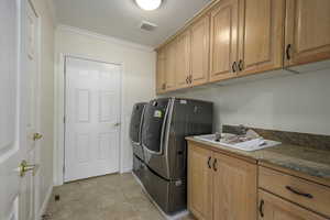 Laundry room featuring separate washer and dryer, sink, cabinets, and ornamental molding