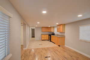 Kitchen featuring light hardwood / wood-style floors, black range with gas stovetop, sink, and light brown cabinetry