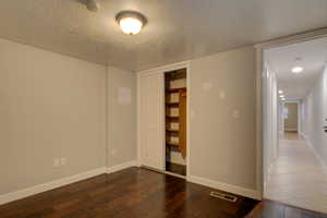 Empty room featuring a textured ceiling and dark wood-type flooring