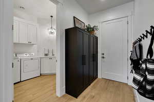 Washroom featuring cabinets, sink, light hardwood / wood-style flooring, independent washer and dryer, and a notable chandelier