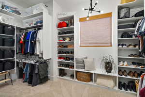 Walk in closet with light carpet and a chandelier