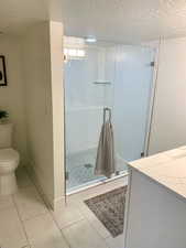 Bathroom with tile patterned floors, a textured ceiling, and an enclosed shower