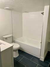 Full bathroom featuring vanity, tile patterned flooring, toilet, a textured ceiling, and shower / bath combination