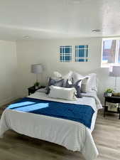 Bedroom with a textured ceiling and light hardwood / wood-style flooring