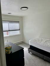 Carpeted bedroom with baseboard heating and a textured ceiling