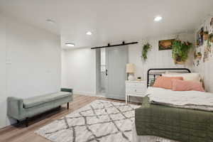 Bedroom featuring light wood-type flooring and a barn door